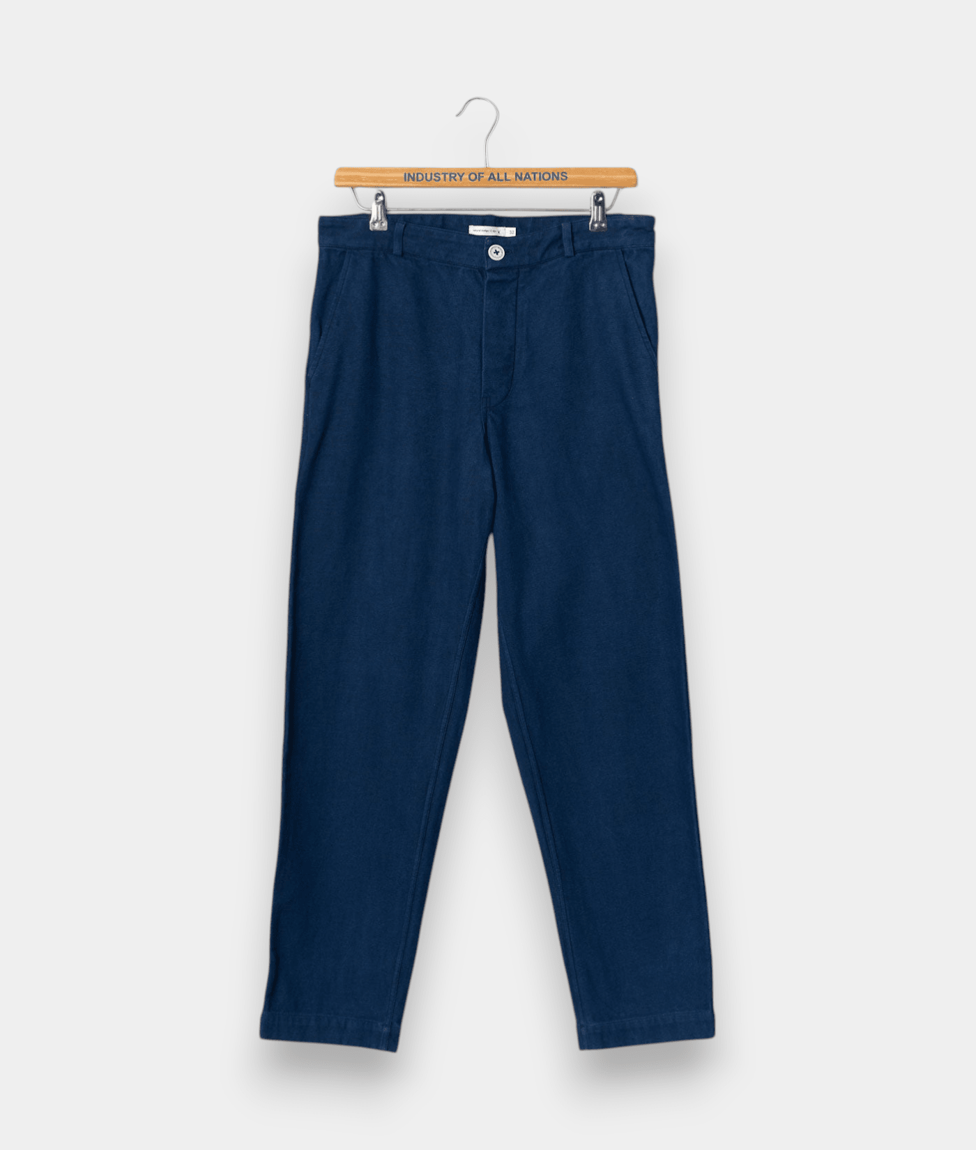 Navy blue cotton chinos on wooden hanger with "Industry of All Nations" text - Industry of All Nations
