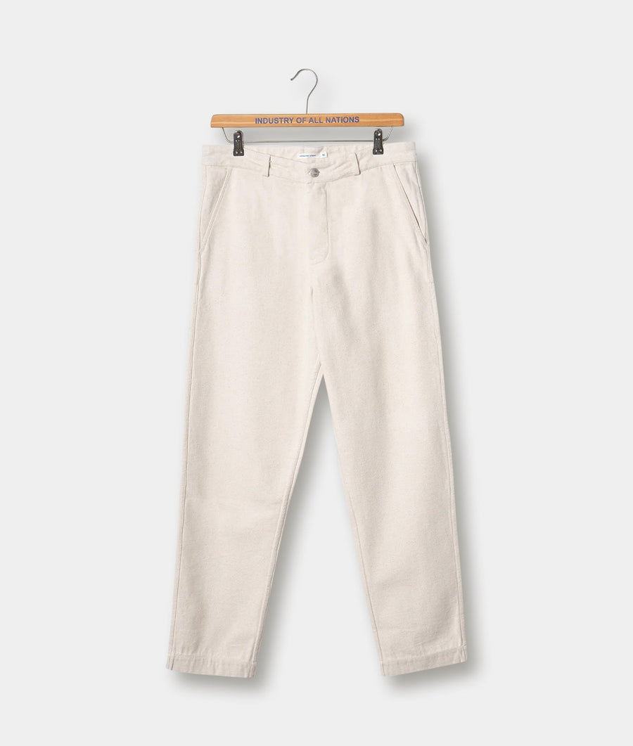 White cotton chino pants displayed on a wooden hanger with the brand name "Industry of All Nations" text on the hanger - Industry of All Nations
