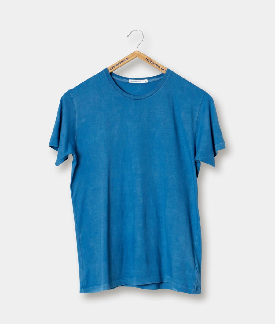 A light blue t-shirt hanging from a wooden hanger with the Industries Nations logo - Industry of All Nations.