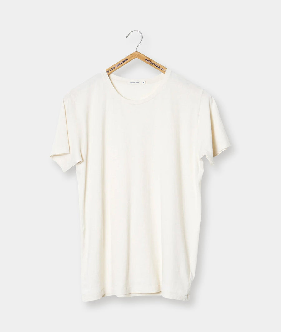 A plain white t-shirt hanging on a wooden hanger with the brand label "Industria di 1" - Industry of All Nations