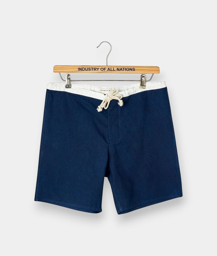 Navy blue drawstring shorts displayed on a wooden hanger with "Industry of All Nations" text - Industry of All Nations