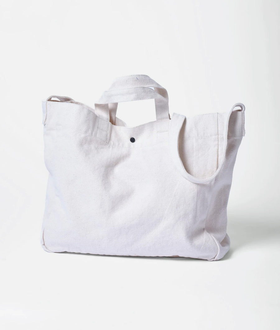 A white, reusable tote bag with a black snap closure, displayed on a plain background - Industry of All Nations