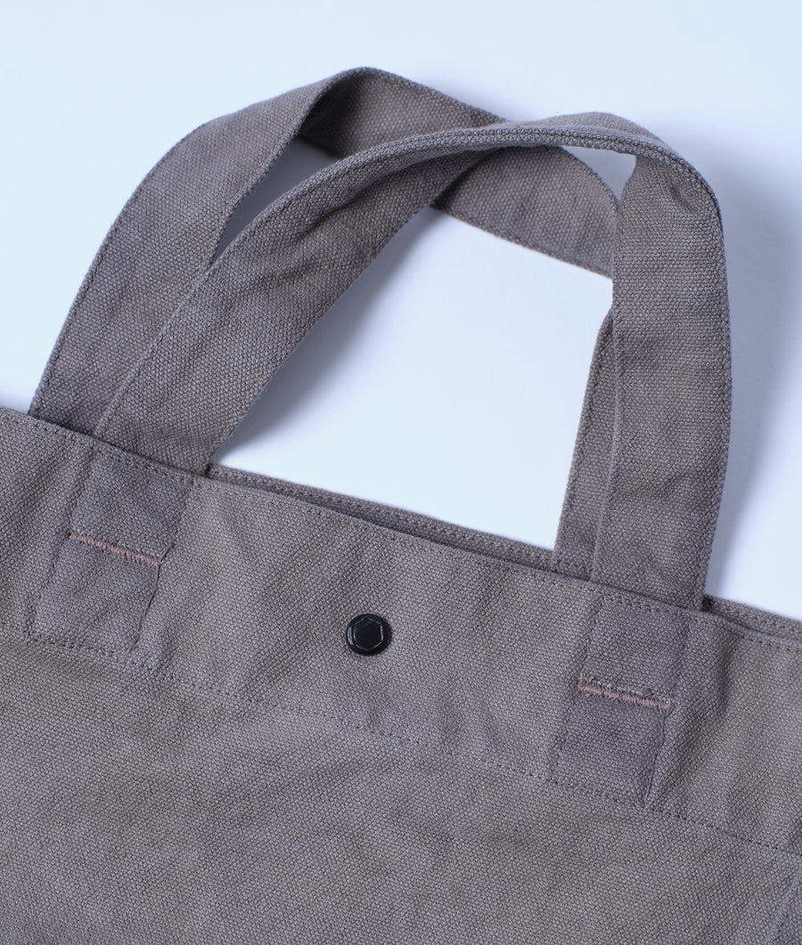 Flat lay of a gray cotton tote bag with a single button closure detail - Industry of All Nations
