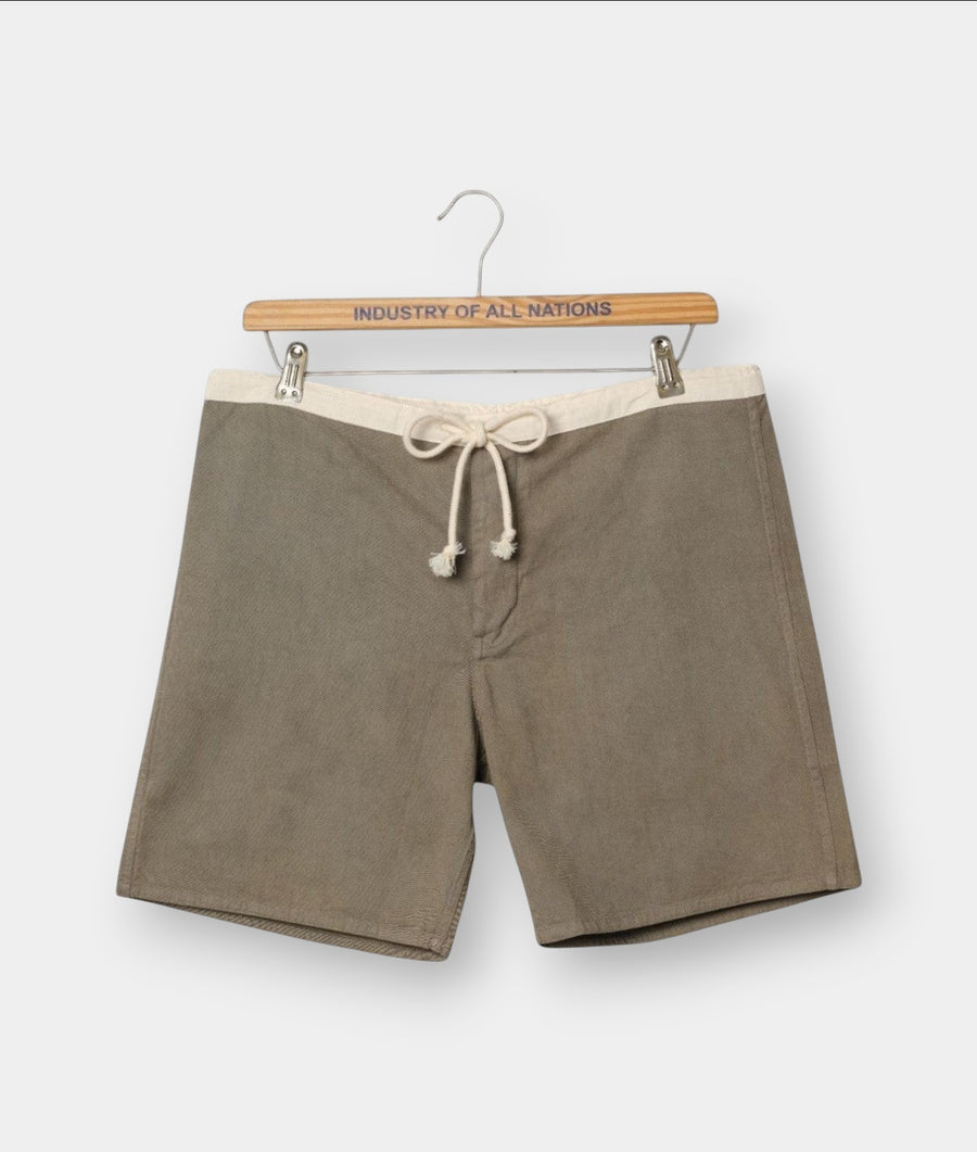 Industry of All Nations organic cotton boardshorts in olive green with a cream waistband and drawstring tie.