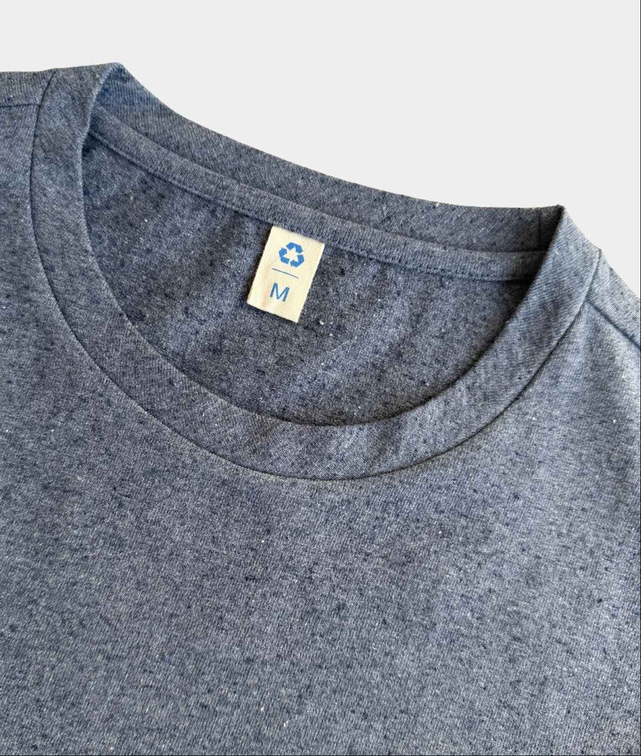Close-up of a heather gray crewneck t-shirt showing the inner neck label with a blue recycling symbol and size 'M'.