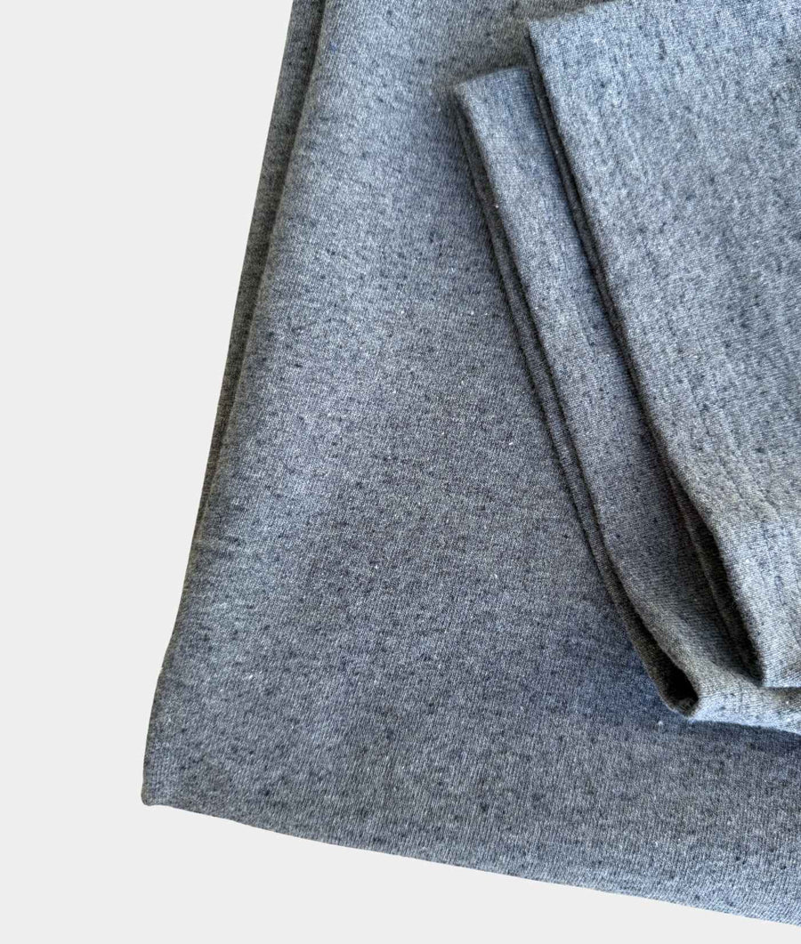 A close-up of folded heather gray fabric, showing the soft texture and woven pattern against a plain light background.