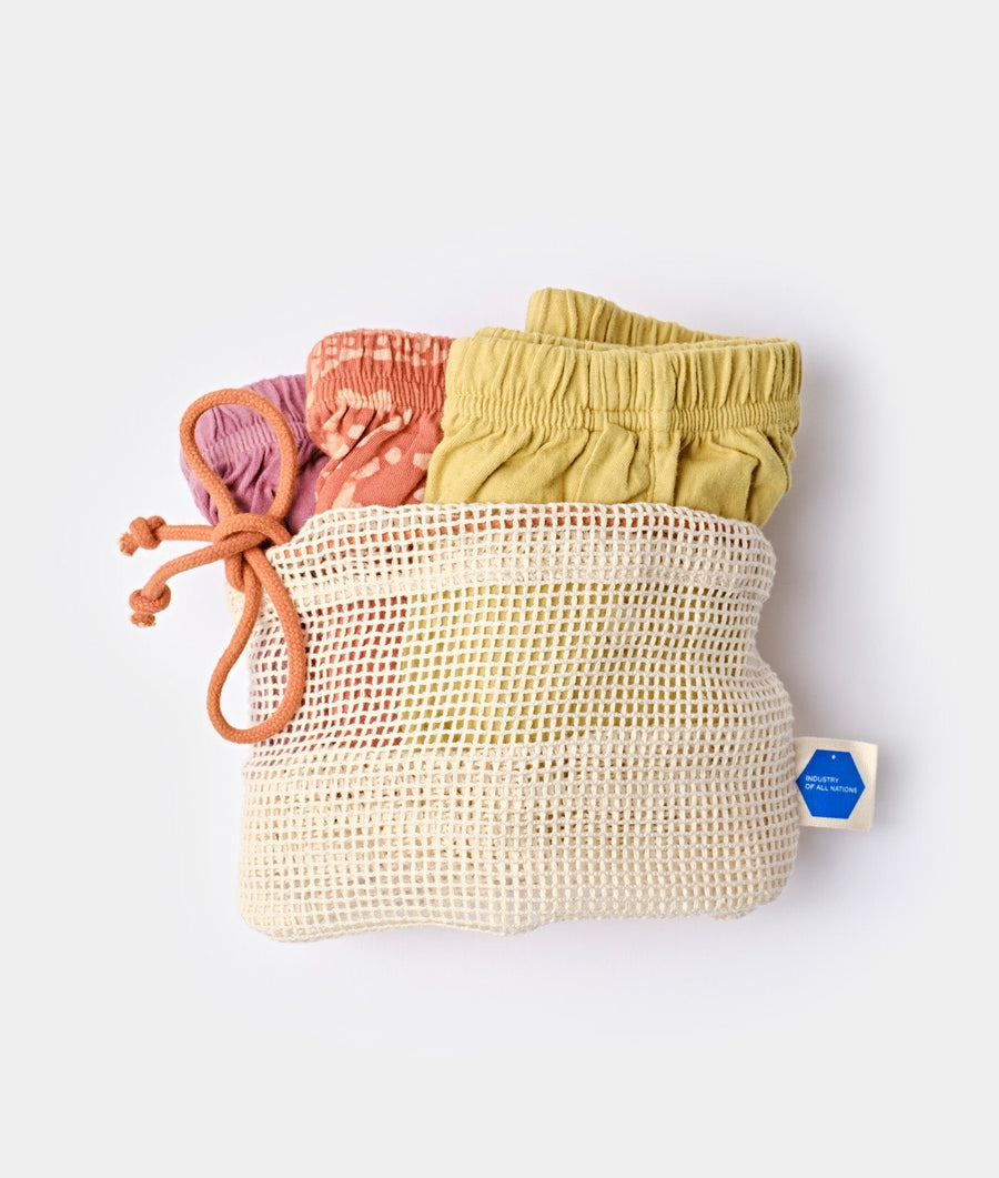 Mesh drawstring bag in beige with colorful drawstrings, displayed in a flat lay - Industry of All Nations