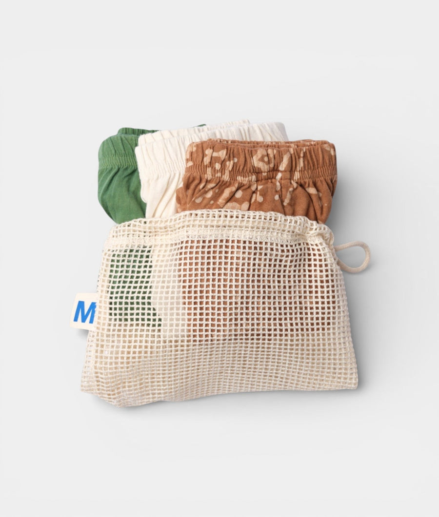 Flat lay of a mesh produce bag with green and brown drawstring-waist pants in a neutral color palette - Industry of All Nations
