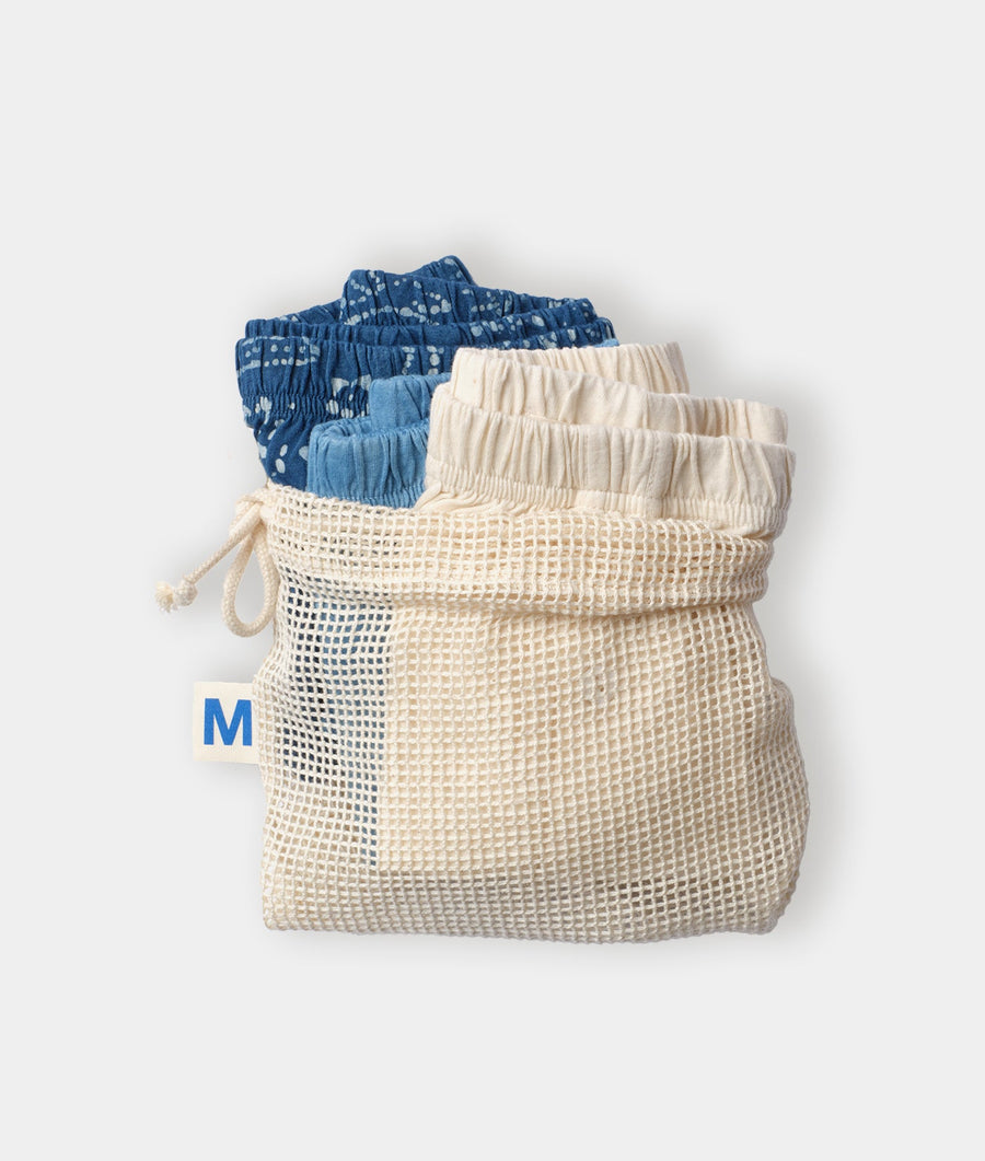 Two pairs of loose, lightweight drawstring pants in shades of blue and cream, displayed in a flat lay on a white background - Industry of All Nations