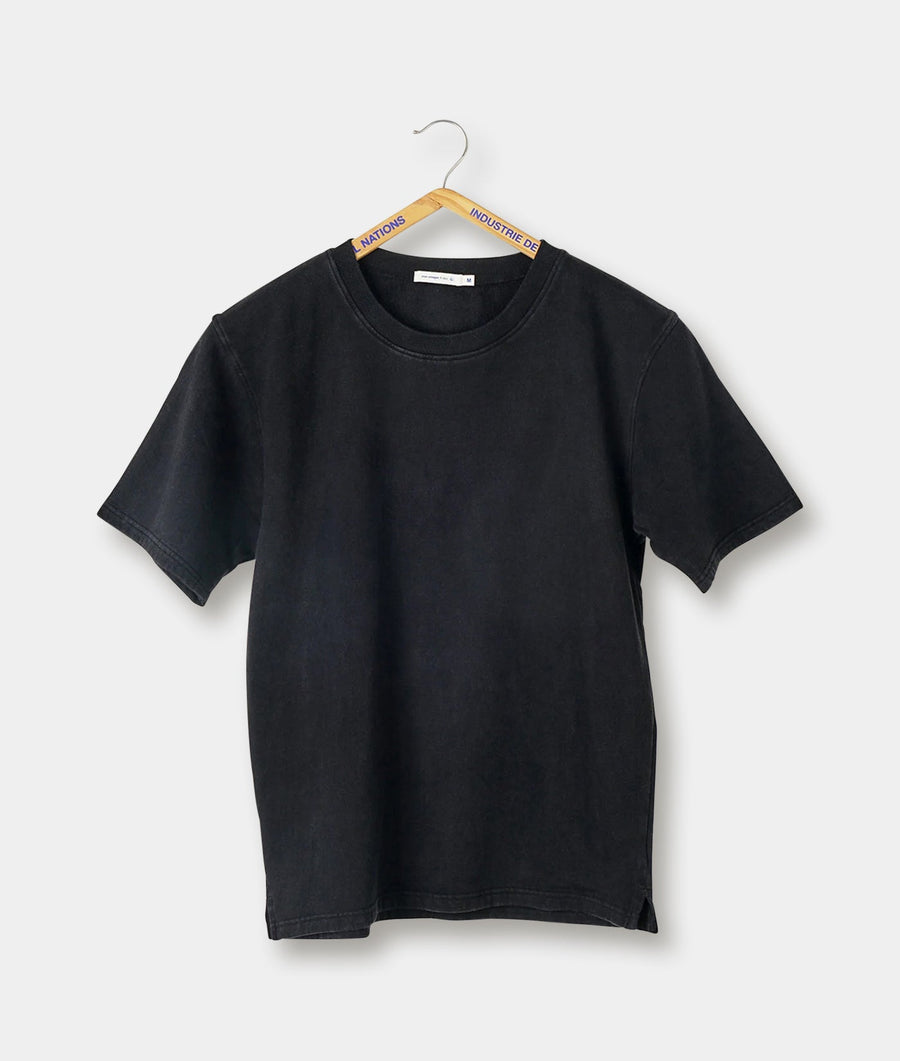 A plain, black short-sleeve t-shirt hanging on a wooden hanger with a branded tag - Industry of All Nations