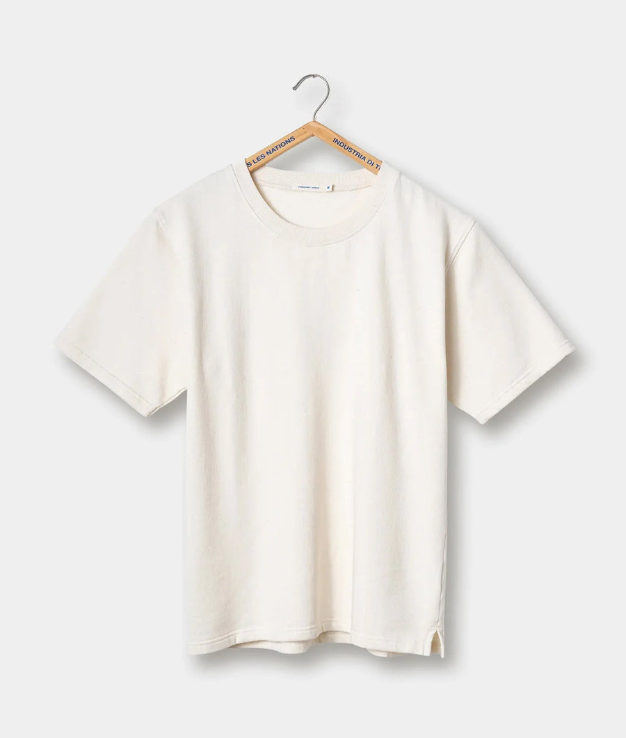 A cream-colored t-shirt displayed on a hanger with the brand name "Industria di T" - Industry of All Nations