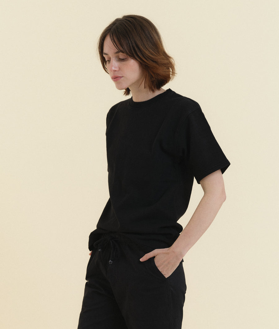 A model wearing a black short-sleeved t-shirt from Industry of All Nations.