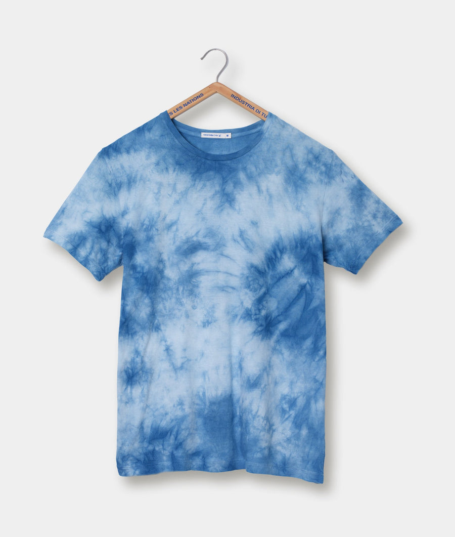 A tie-dye patterned blue cotton t-shirt hanging on a wooden hanger - Industry of All Nations