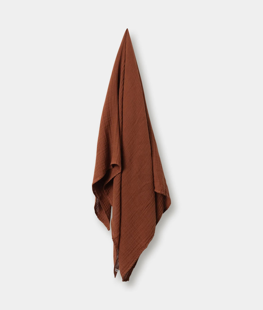 A folded rusty-colored cotton blanket or throw displayed against a white background - Industry of All Nations