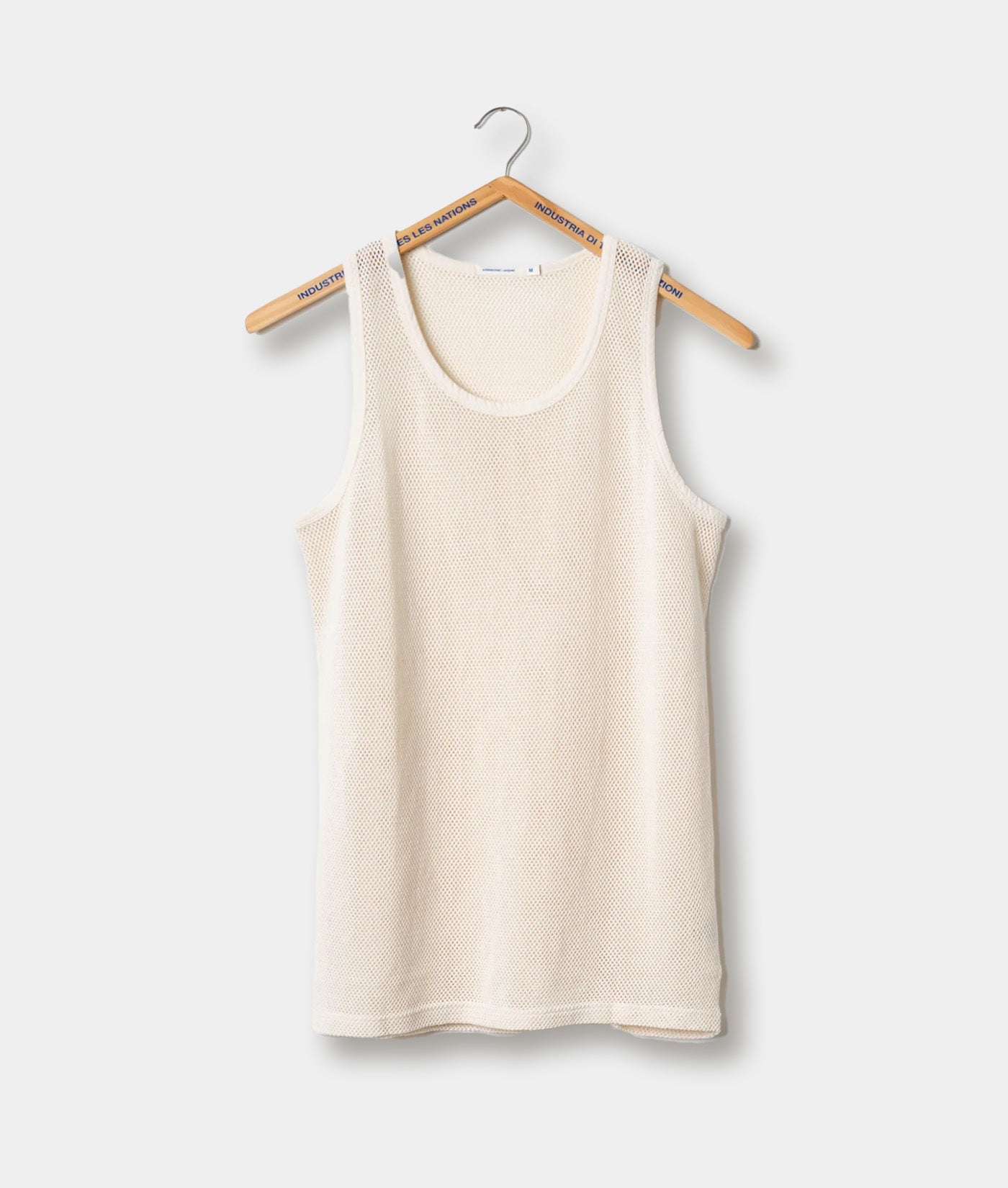 A cream-colored, mesh-textured tank top hanging on a wooden hanger - Industry of All Nations