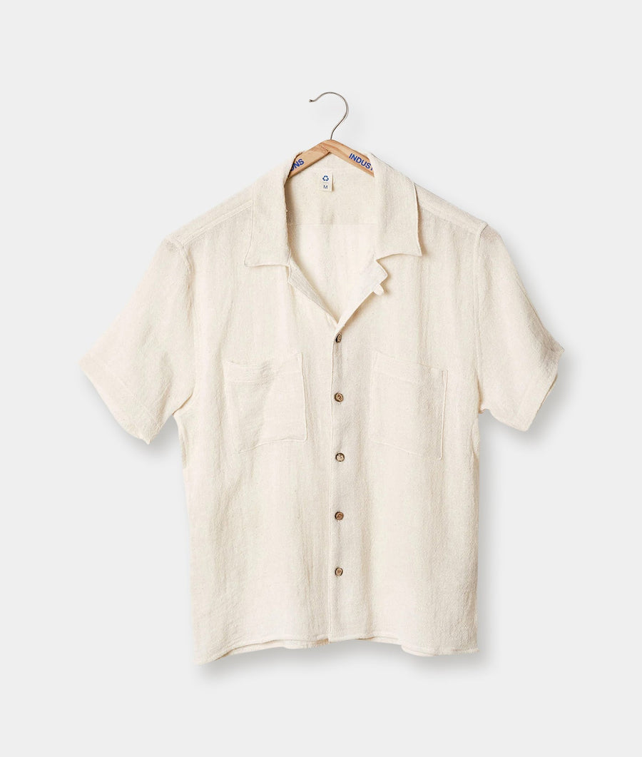 A beige linen short-sleeve button-up shirt displayed on a hanger - Industry of All Nations