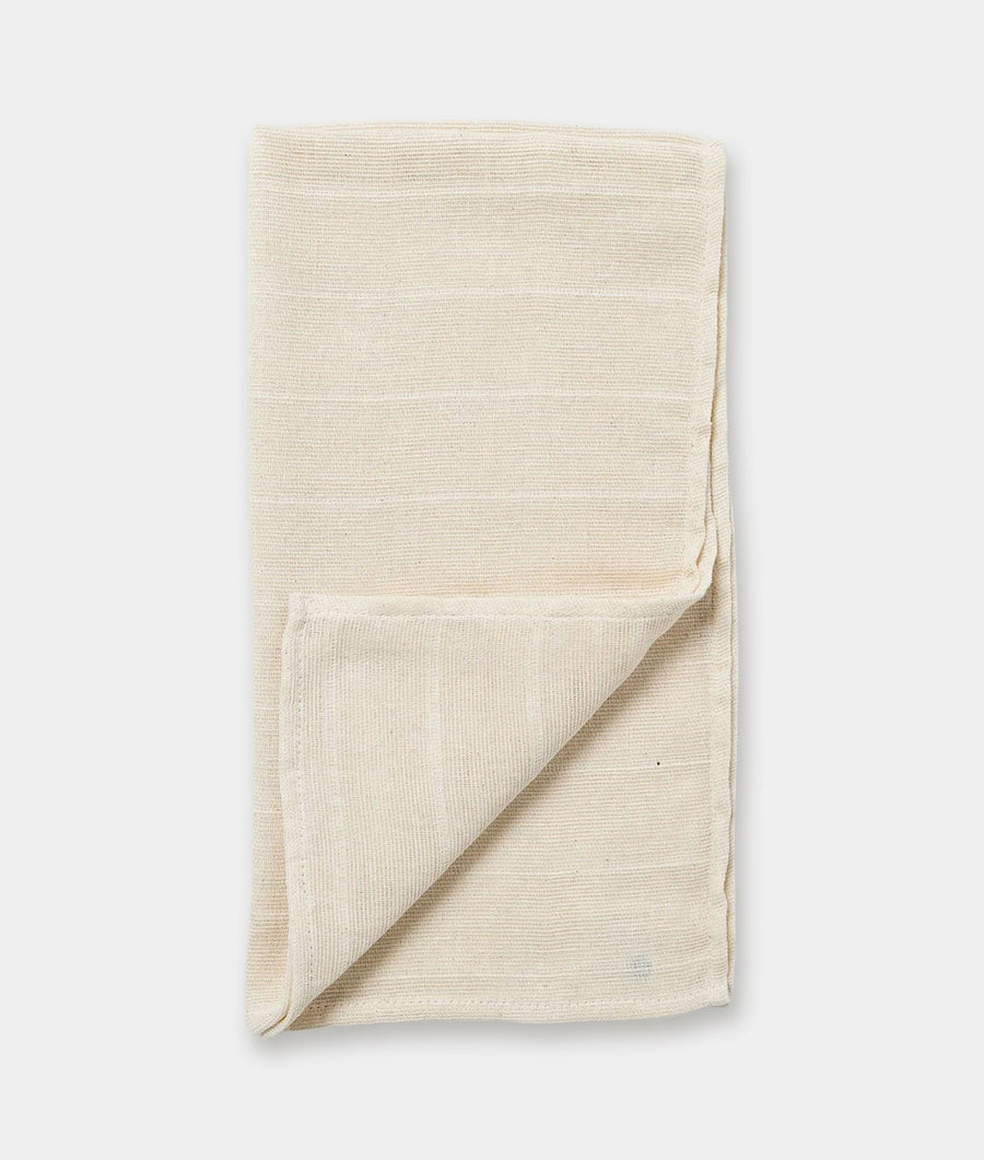 Folded beige organic cotton knit blanket or throw, displayed flat on a plain background - Industry of All Nations