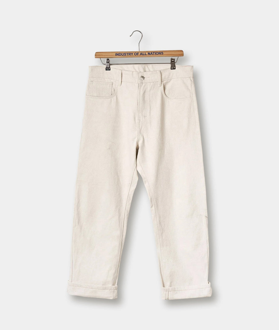Cream-colored denim pants displayed on a wooden hanger with the brand name "Industry of All Nations" printed on the hanger - Industry of All Nations