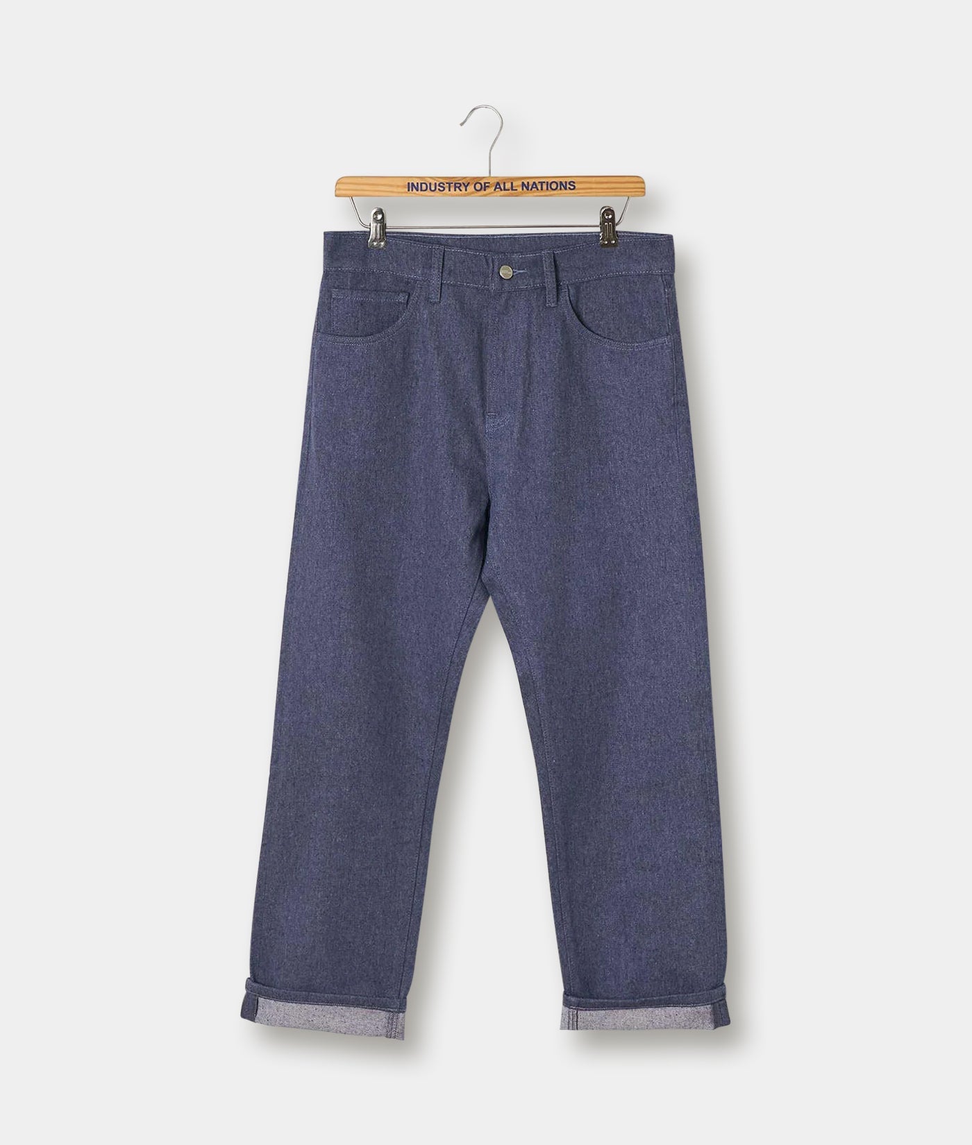A pair of dark grey denim pants hanging on a wooden hanger with "Industry of All Nations" text - Industry of All Nations