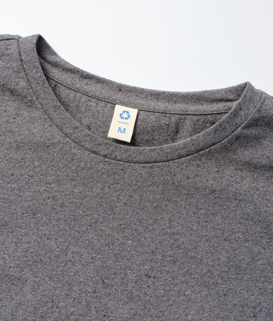 A close-up image of the neckline of a grey cotton t-shirt displaying the recycling symbol and size tag - Industry of All Nations