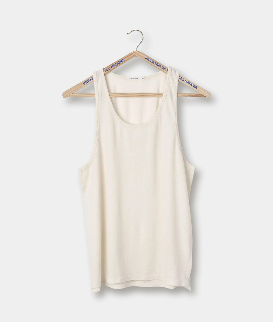A white, sleeveless racerback tank top hanging on a wooden hanger with the brand name "All Nations" printed along the sides - Industry of All Nations