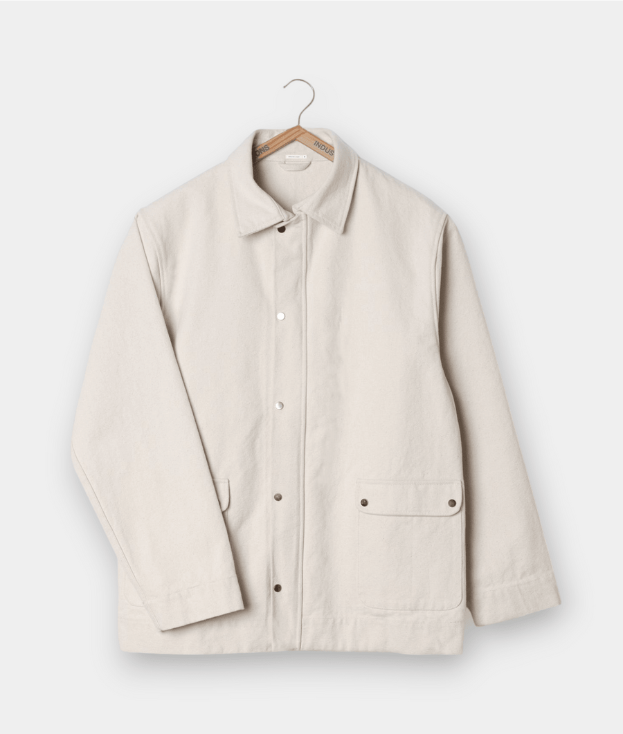 Cream-colored lightweight jacket displayed on a wooden hanger - Industry of All Nations