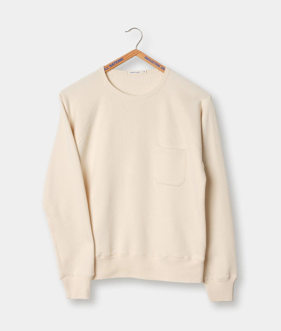 A beige crewneck sweatshirt with a front pocket, displayed on a hanger - Industry of All Nations