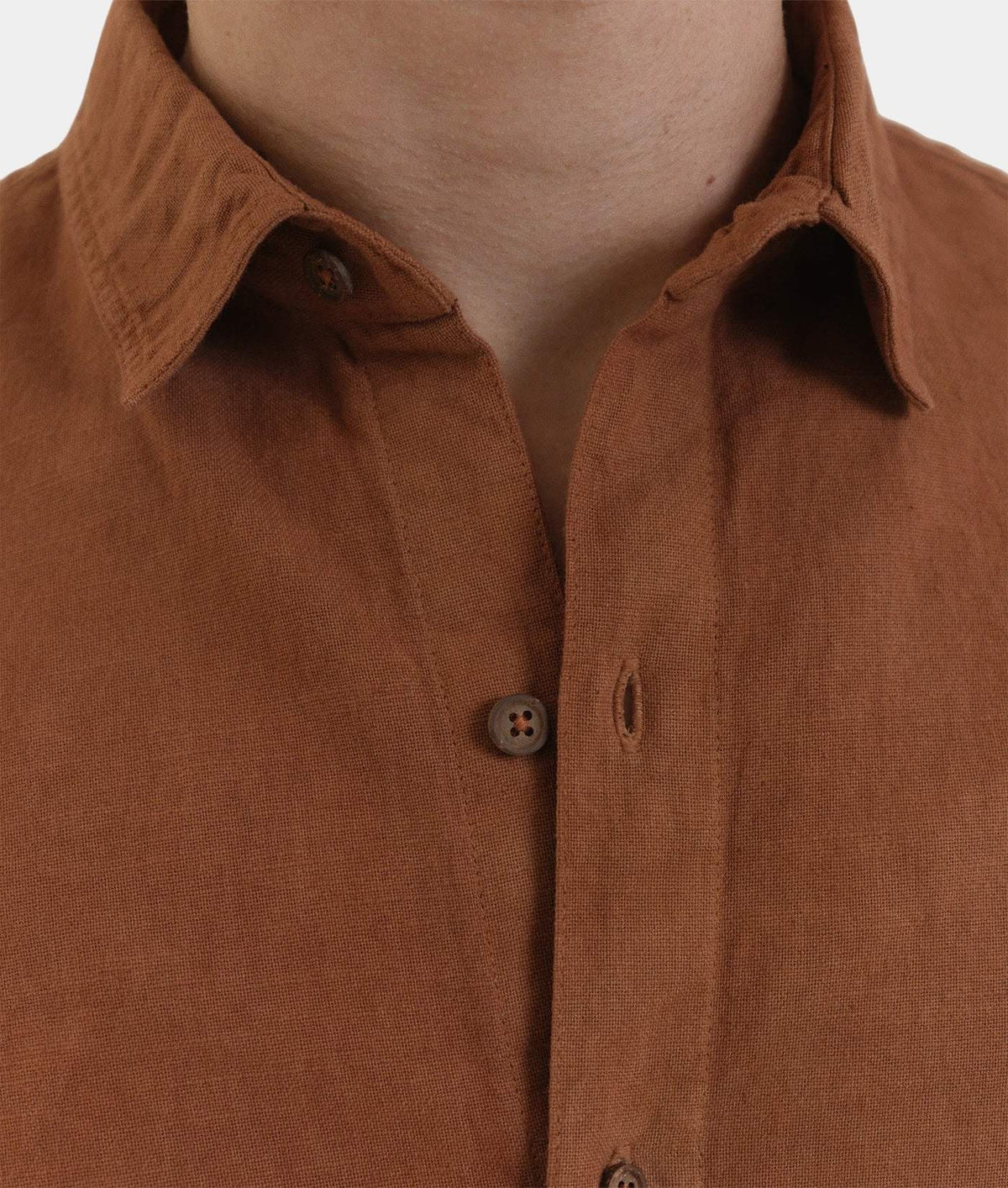 Close-up of a brown linen button-down shirt worn by a model, showing the collar, fabric texture, and buttons.
