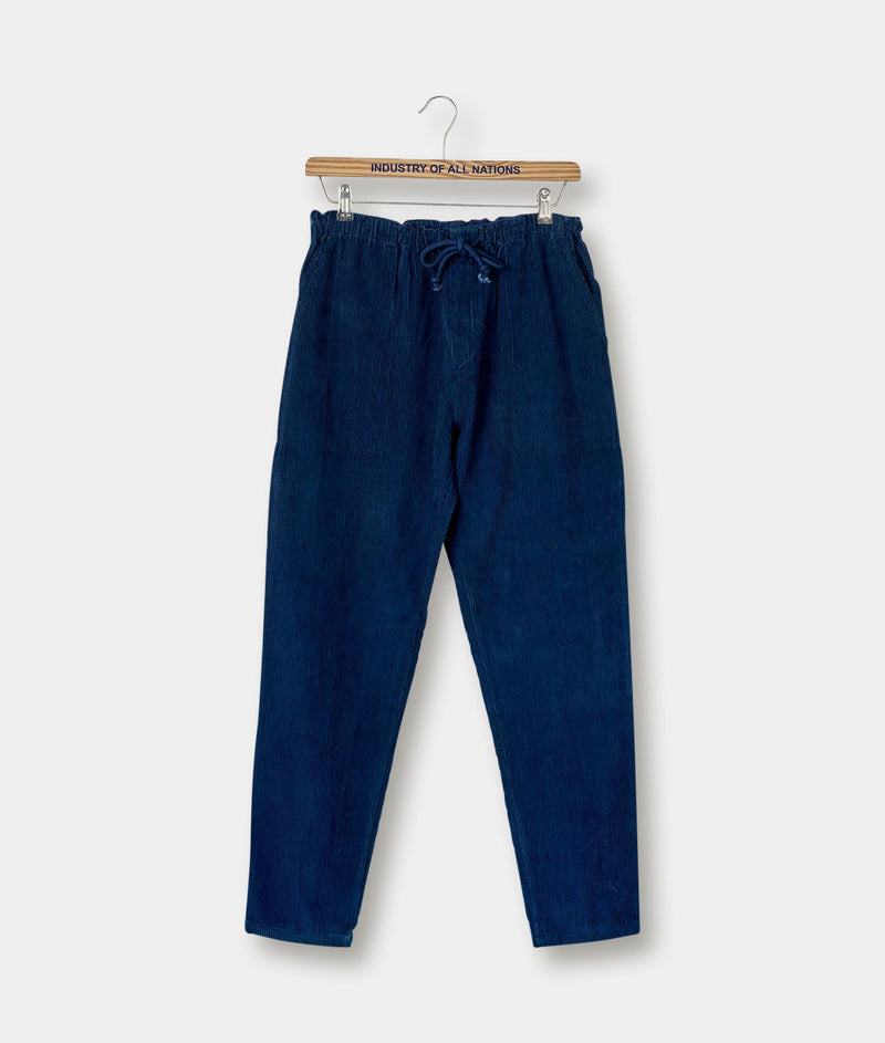 A pair of navy blue drawstring pants hanging on a wooden hanger with "Industry of All Nations" branding - Industry of All Nations