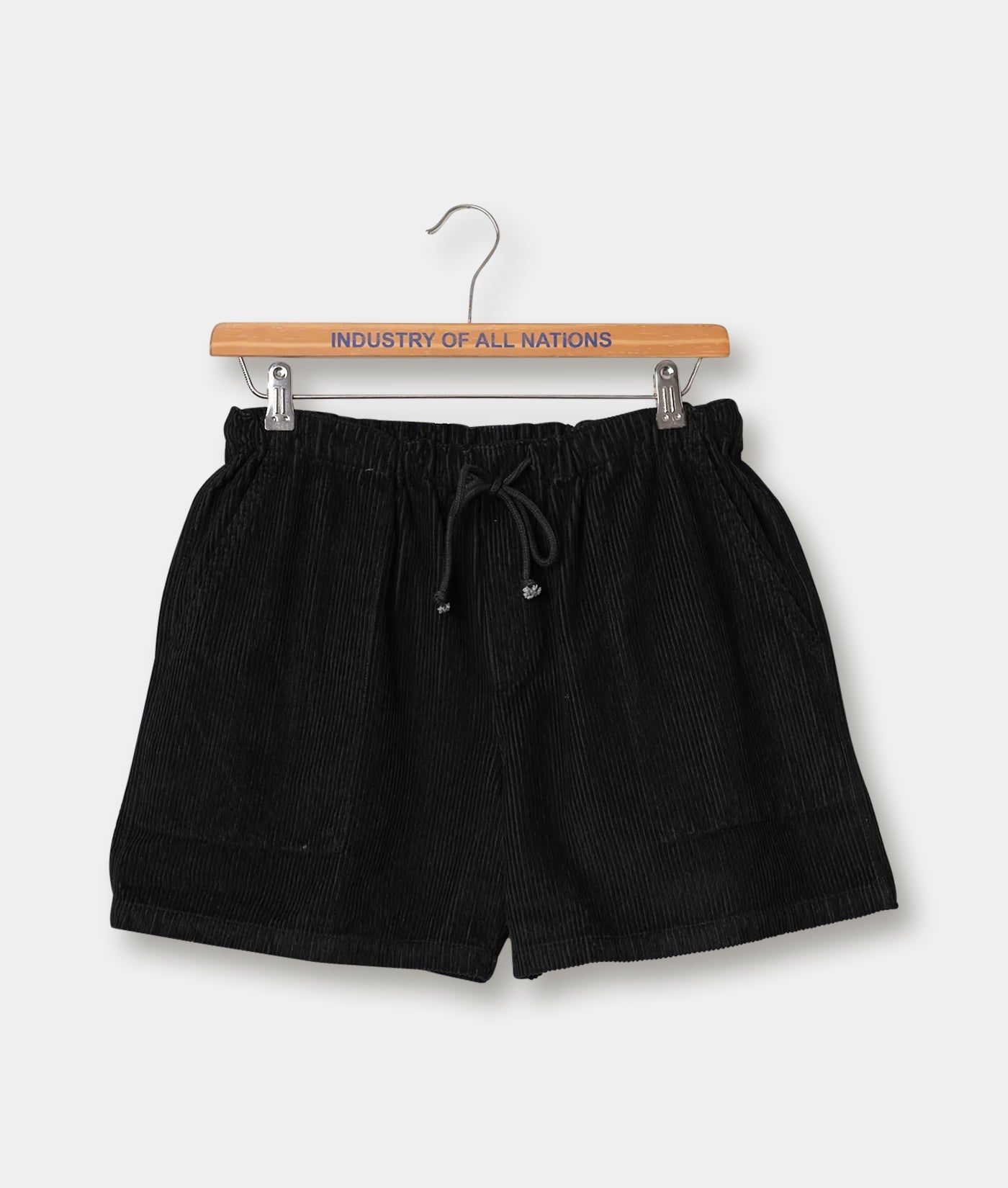 Black pleated shorts with a drawstring waist displayed on a wooden hanger with "INDUSTRY OF ALL NATIONS" text - Industry of All Nations