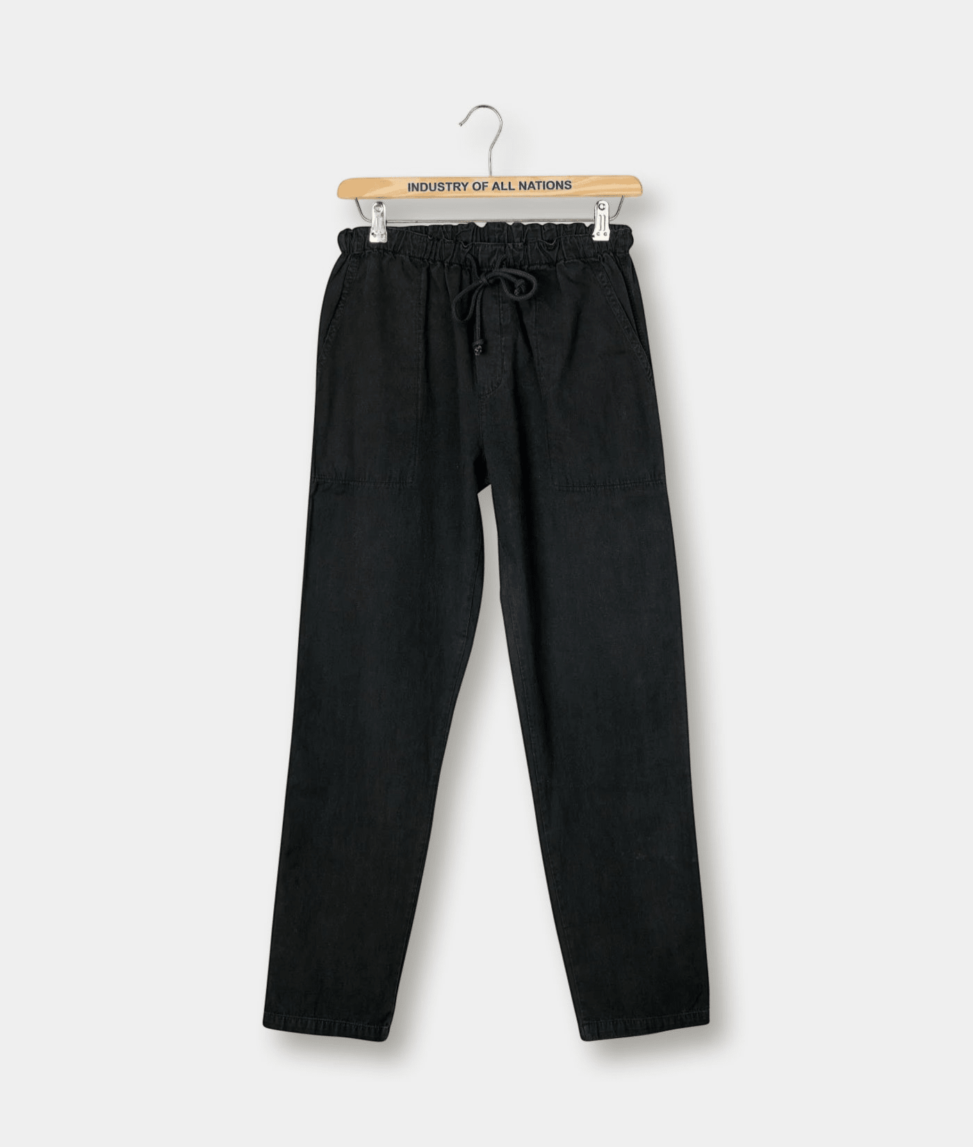 Black drawstring pants hanging on a wooden hanger with "Industry of All Nations" logo - Industry of All Nations