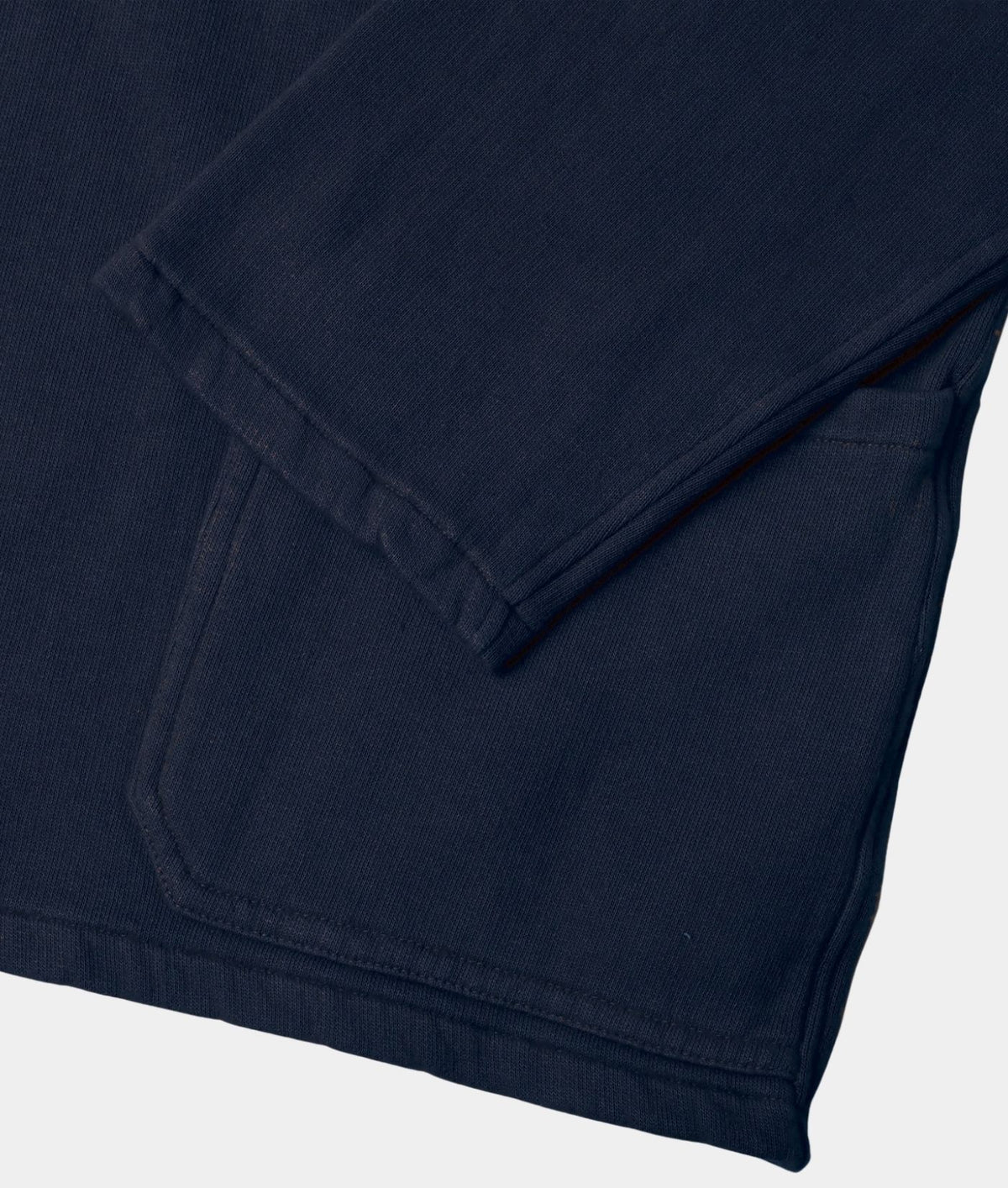 Close-up of a dark navy blue garment, showing folded fabric and a stitched pocket detail against a light gray background.