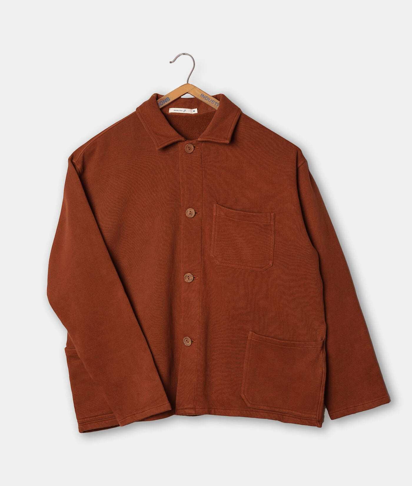 A brown button-up jacket with pockets, displayed on a hanger - Industry of All Nations