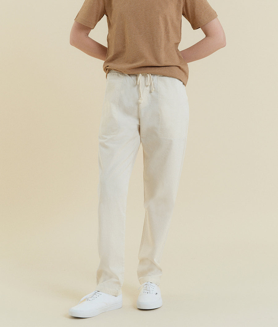 Beige t-shirt and white drawstring pants worn by a person standing against a plain background - Industry of All Nations