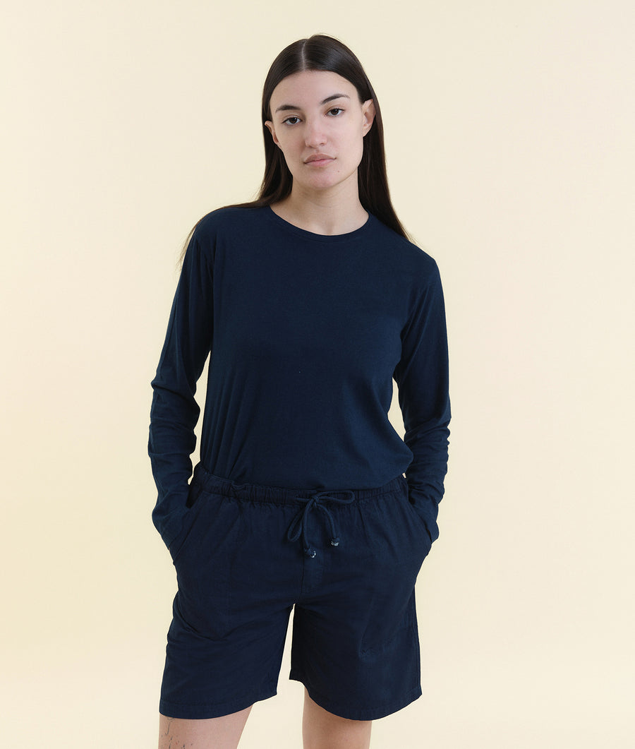 A woman in a navy blue long-sleeved top and matching shorts standing against a beige background - Industry of All Nations