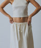 Woman wearing an off white ribbed tank top and cotton maxi skirt against a white studio backdrop