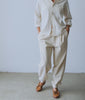 Model in a natural undyed cotton shirt and matching pleated trousers - Industry of All Nations