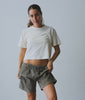 Model wearing a cropped natural white organic cotton tee with grey corduroy pants - Industry of All Nations