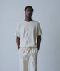 Model in an undyed natural cotton tee and drawstring pants in a pale studio - Industry of All Nations