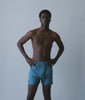 Model in indigo-dyed cotton boxer shorts shown front and back in a bare studio - Industry of All Nations