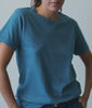 Woman turning in a mid-blue indigo-dyed cotton crewneck tee in a studio - Industry of All Nations