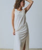 Woman wearing off white cotton slip dress against a white background