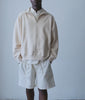 Model in an oversized cream half-zip sweatshirt and natural cotton shorts - Industry of All Nations