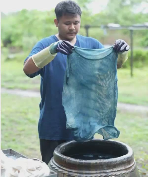 Dye master in India hand-dyeing the IOAN Indigo Netty Tank in a bucket using natural indigo dye