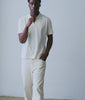 Model wearing an undyed cream organic cotton polo shirt in a soft-lit studio - Industry of All Nations