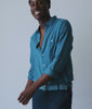 Model in an indigo blue button-down shirt with navy pants and woven belt - Industry of All Nations