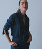 Woman spinning in an indigo-dyed shirt and matching trousers in a bright studio - Industry of All Nations