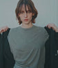 Model in a black cotton blazer over a grey tee and flecked grey trousers by a white wall - Industry of All Nations