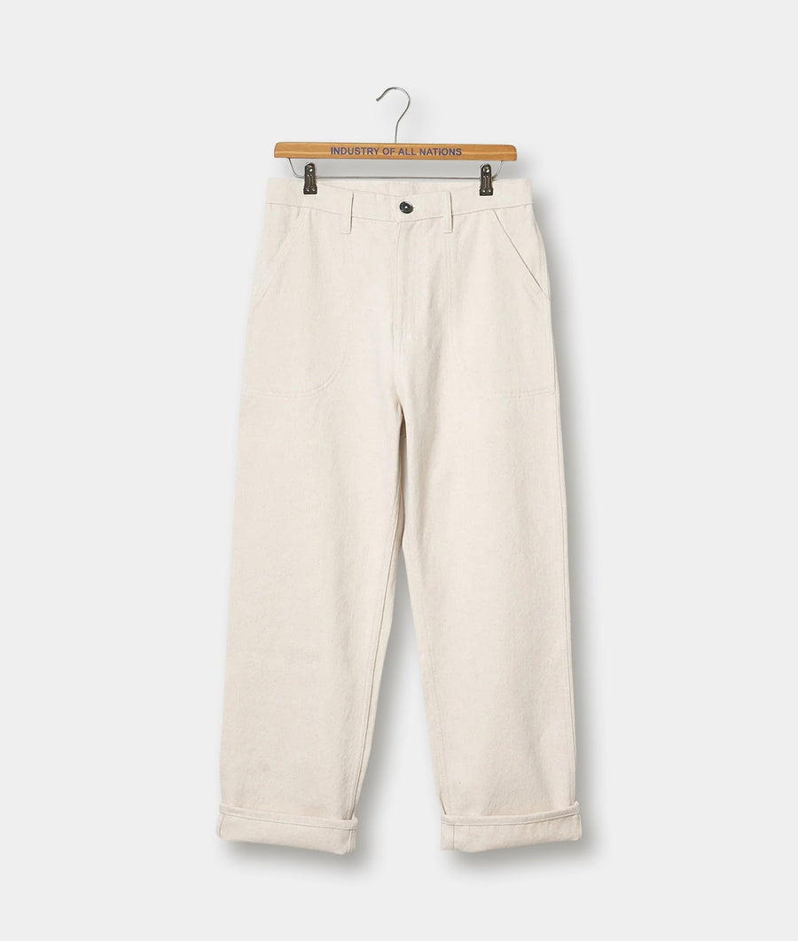 A pair of off-white, loose-fitting, cuffed cotton pants displayed on a wooden hanger with the text "Industry of All Nations" - Industry of All Nations