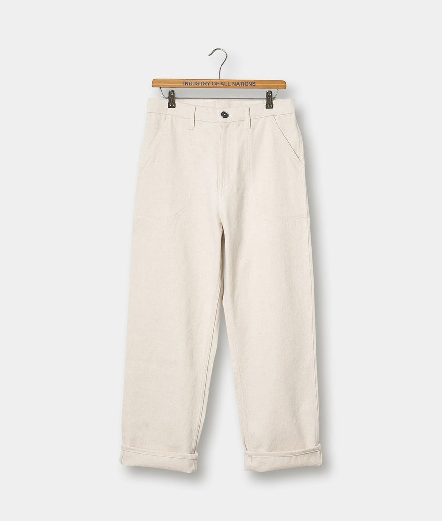 A pair of off-white, loose-fitting, cuffed cotton pants displayed on a wooden hanger with the text "Industry of All Nations" - Industry of All Nations